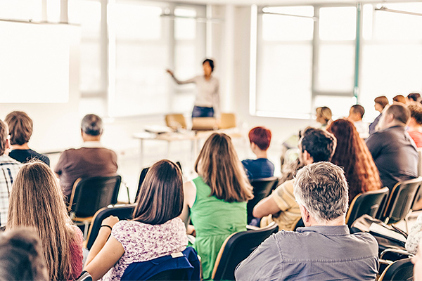 Mehrere Menschen bei einem Vortrag in einem Konferenzraum. Mehrere Menschen bei einem Vortrag in einem Konferenzraum.